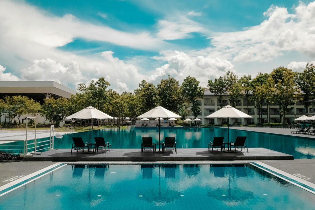Explore a luxurious resort poolside with umbrellas and lounge chairs under a bright sky, perfect for summer vacations.