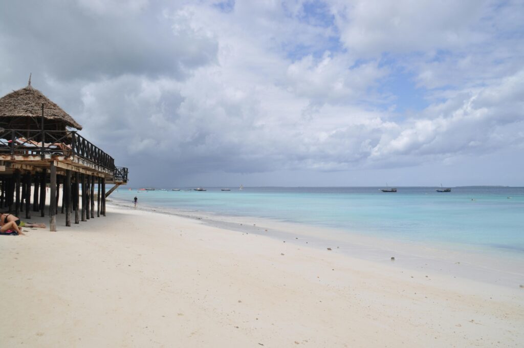 Tranquil beach scene in Nungwi, Tanzania, with azure waters and a wooden pier.