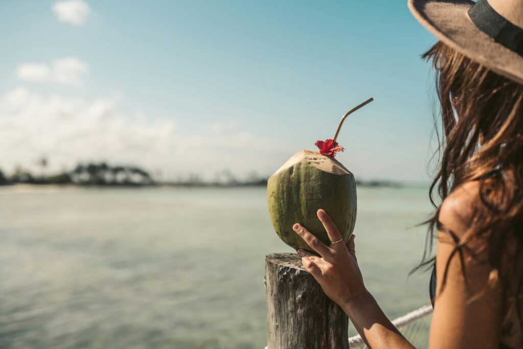 A woman savoring a tropical coconut drink by the serene Zanzibar coastline