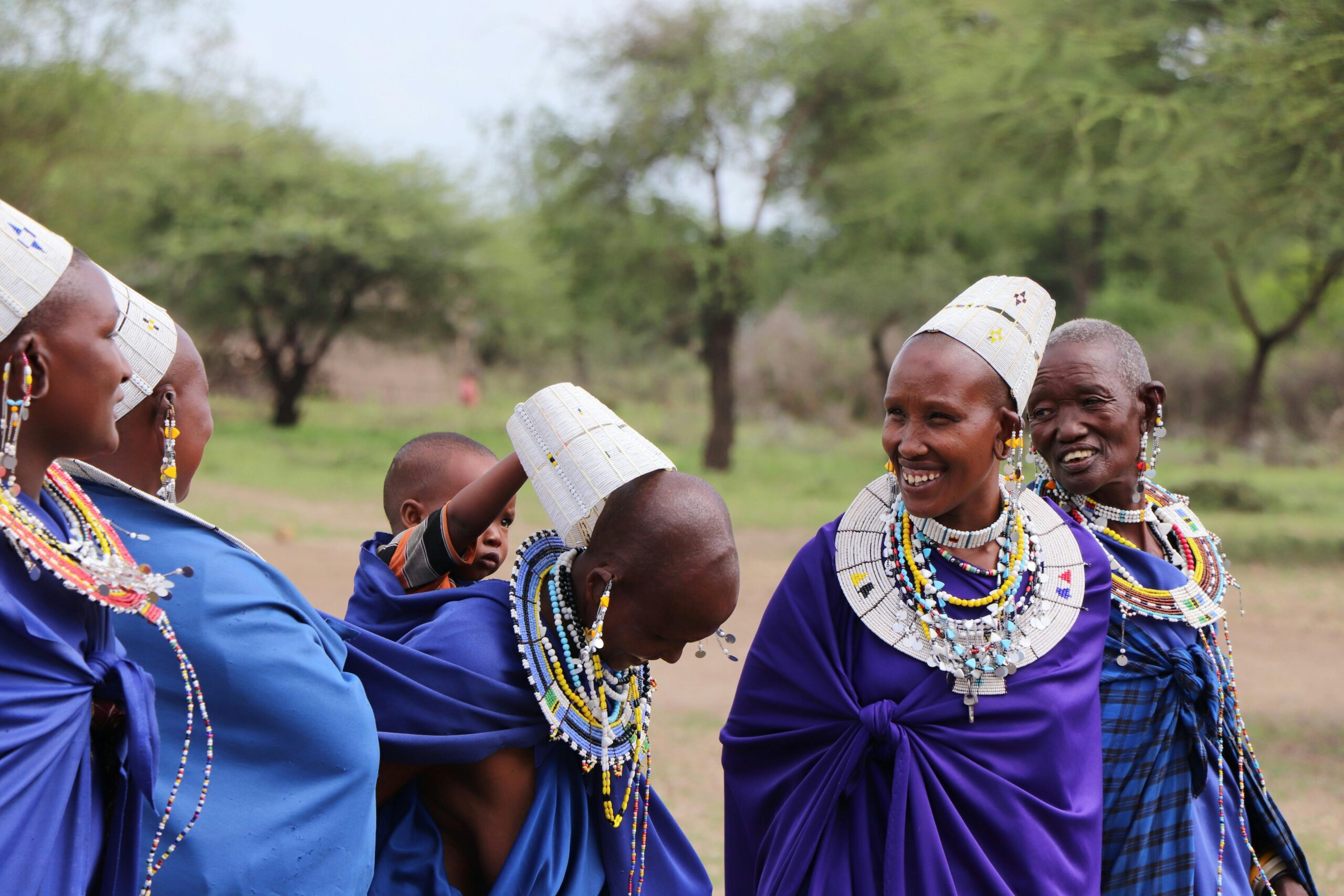 pexels-photo-11679893-11679893 A group of Maasai women and a child in traditional attire sharing joyful moments in Tanzania.